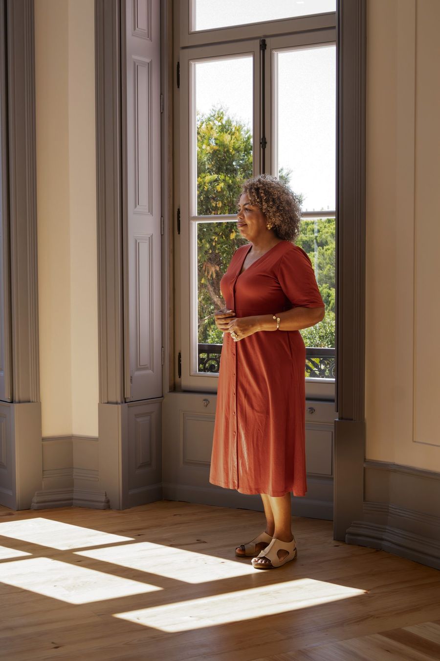 Valéria Araújo junto a uma janela ampla, com luz natural